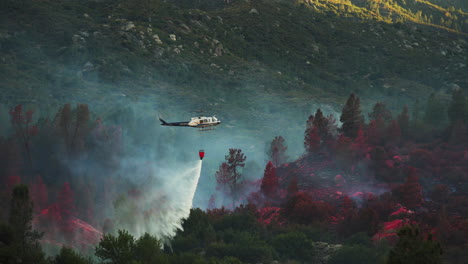 Aerial-fire-fighting,-helicopter-dropping-water-from-suspended-bucket-to-battle-wildfires-in-California,-June-2020