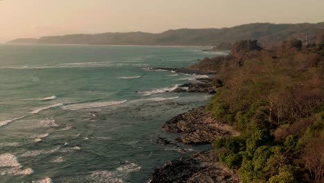 Aerial-tilt-reveal-shot-of-breaking-waves-on-rocky-Costa-Rica-jungle-coastline