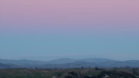 Pink-sky-over-mountain-range-at-sunset,-wide-shot