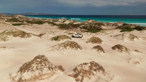 4WD-car-driving-across-sand-dunes-on-the-coast,-Australia,-aerial-view