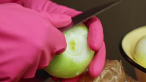 Peeling-onion-skin-wearing-latex-rubber-gloves-closeup