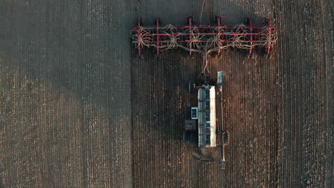 Seeding-in-field-with-tractor-and-seed-drill,-drone-shot