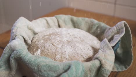 White-Flour-Sprinkled-Onto-The-Top-Of-A-Sourdough-Bread-In-The-Kitchen---zoom-out-slowmo-shot