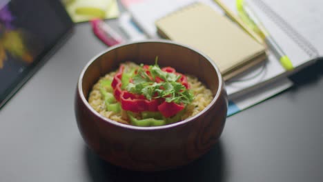 Close-up-man-leaves-wooden-bowl-of-colorful-tasty-ramen-noodle-on-the-desk-table-at-co-working-space-during-lunch-time-slow-motion