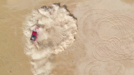 Red-truck-drifting-in-the-desert-sand,-aerial-top-view
