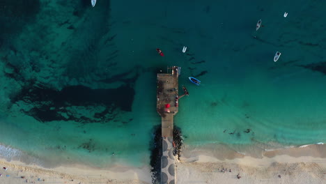 Aerial-top-down-wide-shot-of-the-famous-wooden-pier-and-beach-at-Santa-Maria,-island-of-Sal,-Cape-Verde