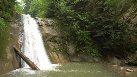 Small-Waterfall-Going-Down-into-Narrow-Lake,-Wide-Shot-4K