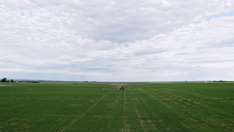 Tractor-Agrícola-Rociando-Productos-Químicos-En-El-Campo-De-Trigo-Grande-N-Saskatchewan,-Canadá---Drone-Aéreo