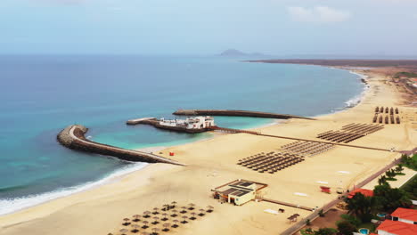 Aerial-shot-of-a-tourist-resort-and-a-long-sandy-beach-with-a-double-breakwater-construction