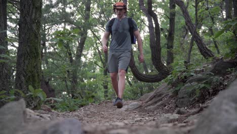 Low-angle-view-of-male-swet-tired-hiker-walking-down-from-the-mountain-trail