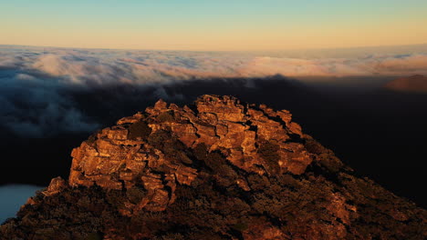 Aerial-view-around-people,-on-the-top-of-the-on-Mount-Hassell-Mountain,-above-clouds,-during-sunset,-in-West-Australia---orbit,-drone-shot