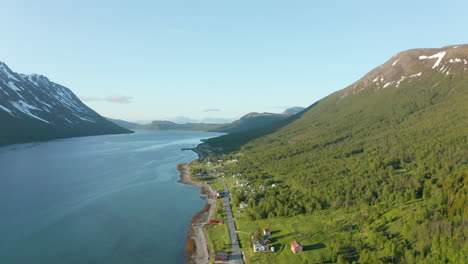 Aerial-flyover-of-Rotsund,-Norway-along-tranquil-fjord-and-mountain-landscape