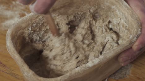 Mixing-Bread-Dough-Mixture-In-A-Container-With-A-Wooden-Spoon---close-up-slowmo