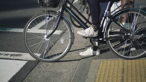 Japanese-People-Riding-Bicycles-Waiting-To-Cross-The-Road-In-Tokyo,-Japan