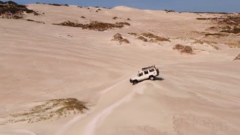 Aerial-of-safari-jeep-vehicle-driving-across-the-sand-dunes