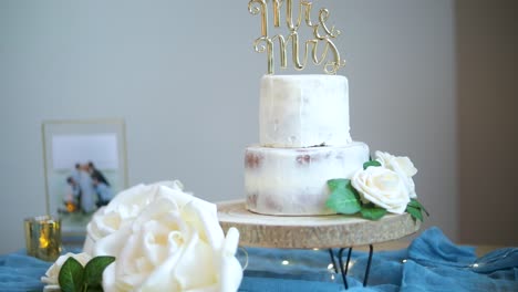 Simple-two-layer-decorative-white-icing-wedding-cake-with-Mr-and-Mrs-letters-and-white-flowers-for-celebratory-day,-close-up-zoom-in