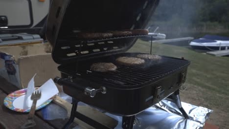 Man-Putting-Sausage-Together-With-The-Beef-Patties-And-Closing-The-Griller