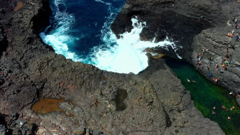 Aerial-shot-of-a-rocky-lagoon-and-natural-sea-pool-with-swimmers