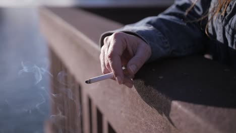 Cigarette-smoldering-in-woman's-hand