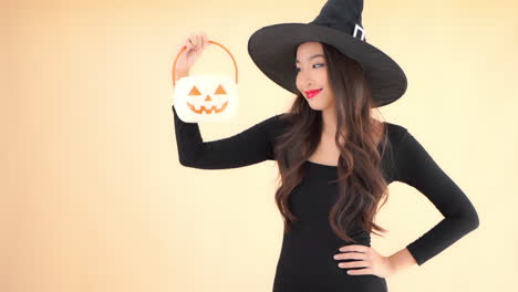 A-very-sexy-witch-lift-up-a-plastic-jack-o-lantern-into-view