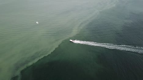 Motorboat-Sailing-Swiftly-Across-The-Silty-Sea-Water---aerial-drone