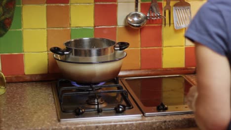 Creating-a-bain-marie-to-boil-a-milk-icing-on-a-stove-in-a-colorful-tile-kitchen