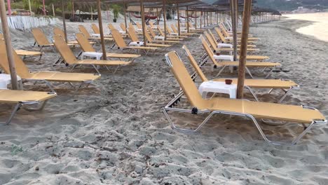 View-on-orange-vacant-sunbeds-under-straw-sun-umbrellas-due-to-Covid-19-travel-ban-and-economic-recession-in-4k