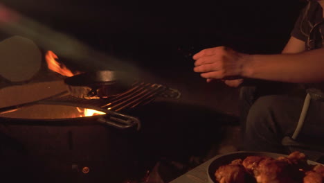 Barbecuing-food-over-fire-pit-on-camping-trip-at-night