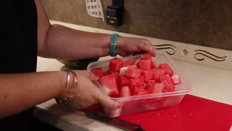 Woman-picking-up-cut-watermelon-pieces