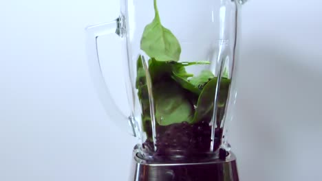 Spinach-dropping-into-blender,-over-blueberries,-healthy-shake
