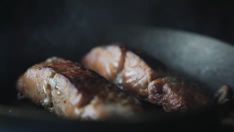 2-salmon-fillets-cooking-and-sizzling-on-a-frying-pan---closeup