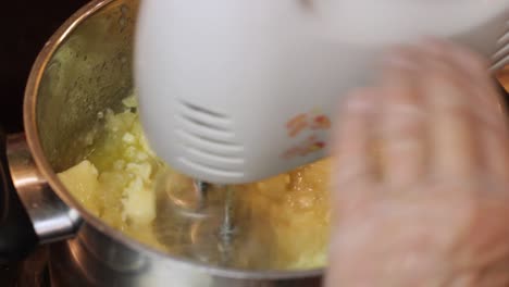 Whisking-warm-butter-and-ingredients-for-a-boiled-icing-recipe-in-a-saucepan