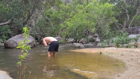 Shirtless-Adult-Male-Standing-In-Swimming-Hole-Washing-Face-In-Emerald-Creek