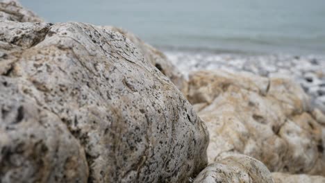 Rocky-pebble-stone-shoreline-with-ocean-waves-background-marine-landscape-close-up-dolly-left-rising
