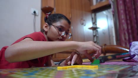 Girl-With-Eyeglasses-Placing-Scrabble-Letter-Tiles-On-Game-Board-In-The-House---close-up,-low-angle-shot