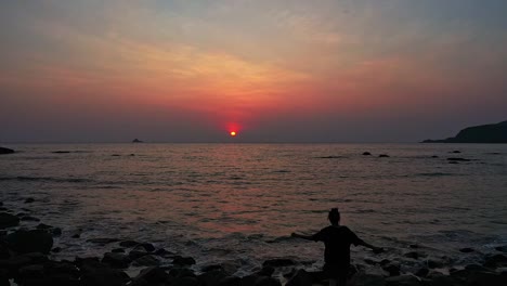 Mädchen-Geht-Auf-Der-Felsigen-Küste-Von-Goa-Beach-Mit-Dramatischem-Sonnenunterganghimmel-In-Indien