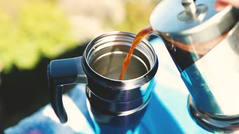French-Press-begins-to-pour-coffee-or-tea-into-a-thermos-on-the-top-of-a-mountain-shot-in-4k-super-slow-motion
