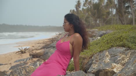 Sexy-Indian-model-sits-on-the-rocks-of-this-coastline-with-waves-crashing-at-the-shoreline-in-slowmotion
