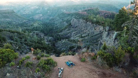 Aerial-View-Of-Motorcycle-And-Camping-Equipment-On-The-Mountain-With-Scenic-View-At-Sunrise