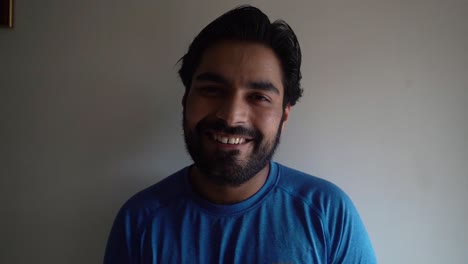 Bearded-Indian-Man-In-Blue-Shirt-Smiling-In-Front-Of-The-Camera---medium-close-up