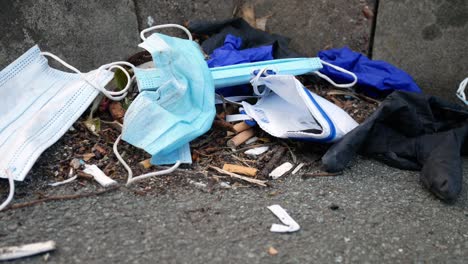 Dirty-disposable-corona-virus-face-masks-and-latex-gloves-among-cigarette-rubbish-on-street-curb-dolly-right