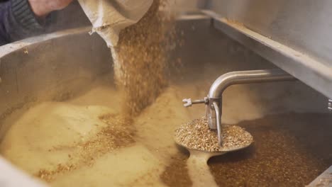Beer-Production---Pouring-Malt-Grains-Into-The-Large-Milling-Tank-In-The-Brewery---close-up-slowmo