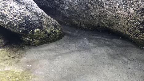 Zeitlupe-Der-Ankommenden-Flut-Zwischen-Zwei-Großen-Felsen-Auf-Sandigem-Meeresboden