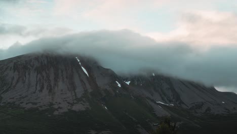 Zeitraffer-Einer-Wunderschönen-Malerischen-Aussicht-Auf-Einen-Großen-Berg,-Während-Wolken-über-Die-Spitze-Des-Berges-Ziehen-Und-Einen-Natürlichen-Fluss-Erzeugen,-Norwegen