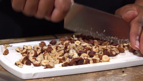 Hands-of-an-African-American-chopping-hazelnuts-with-a-knife---isolated