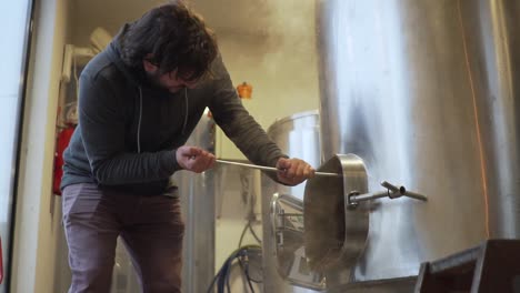 Beer-Production---Brewer-Pulls-Out-Spent-Malt-From-A-Beer-Brewing-Tank-In-The-Brewery---side-view-slowmo