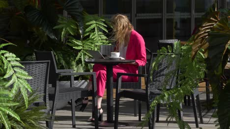 Young-stylish-business-woman-elegantly-sits-outside-office-and-works-with-her-laptop