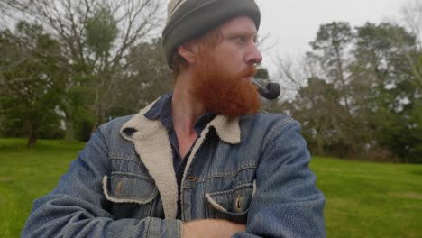 A-shot-of-a-bearded-ginger-mans-face-as-he-smokes-from-a-tobacco-pipe-in-the-woods
