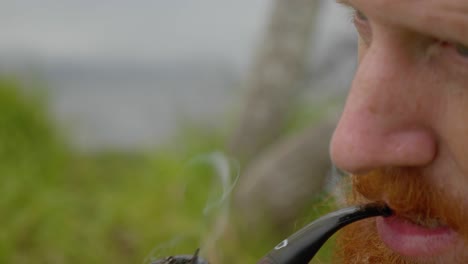 A-close-up-shot-of-a-bearded-ginger-man-lighting-a-tobacco-pipe