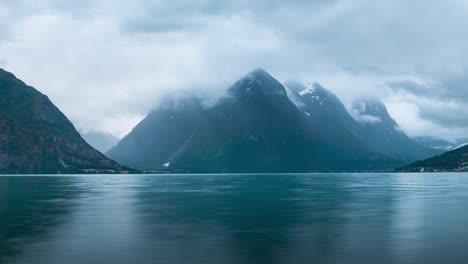 Zeitraffer-Am-Abend,-Auf-Der-Wasseroberfläche,-Blick-über-Einen-Wunderschönen-See-Mit-Schneebedeckten-Bergen-Im-Hintergrund,-Vorbeiziehende-Wolken,-Norwegen